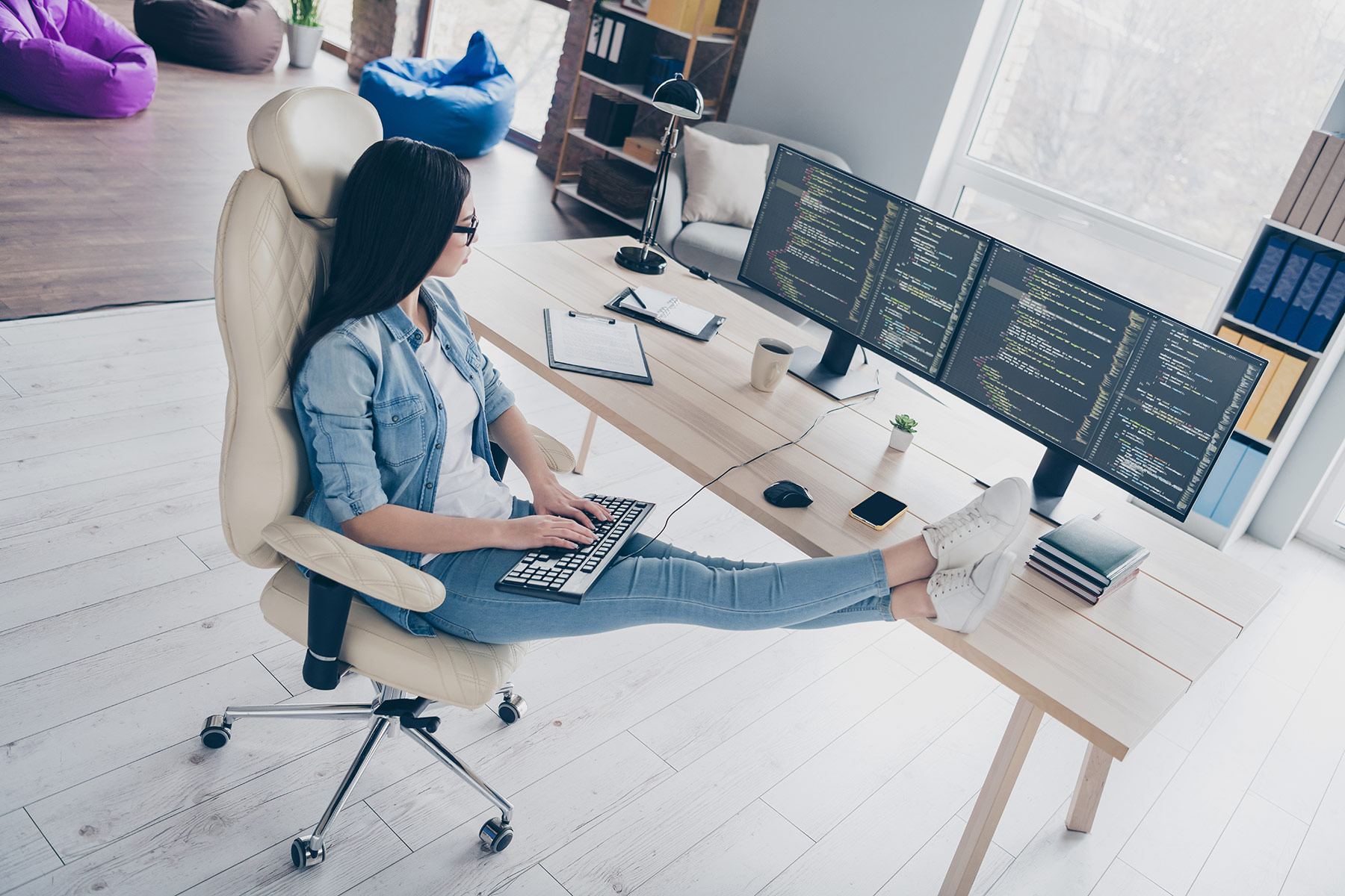 A woman works comfortably at a desk in a modern, hybrid office space that KARDENT architects can expertly design.