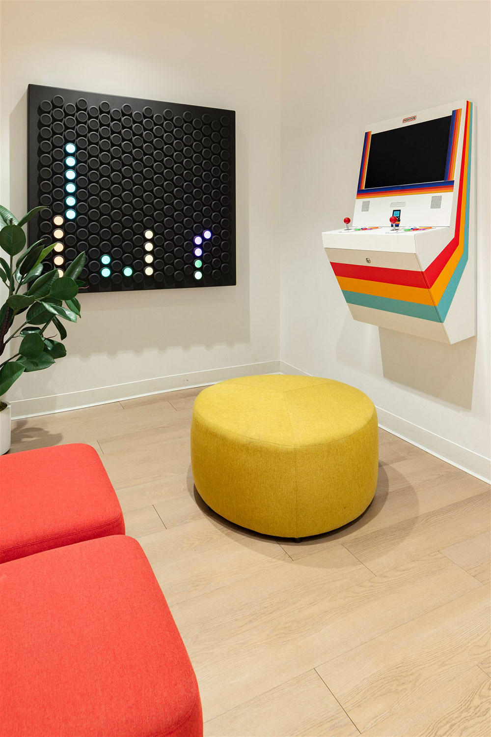 Kids play area in pediatric dental office with wall game board, arcade console, colorful seating, and modern decor