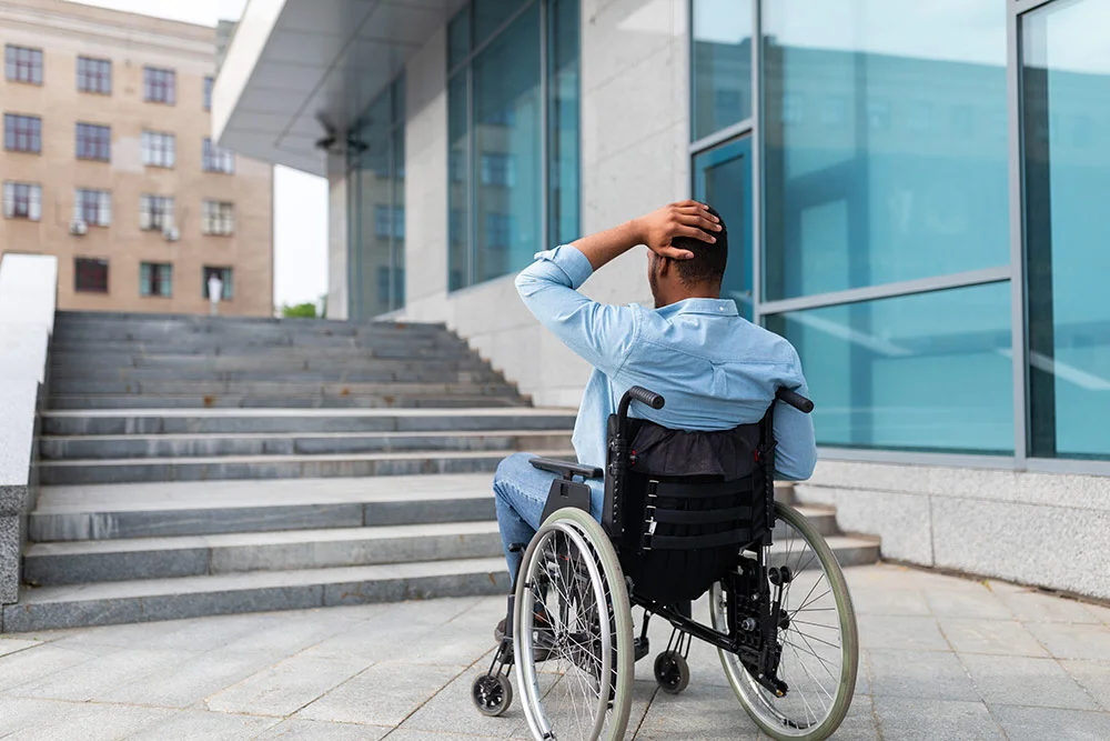 young man in a wheelchair looking at the insurmountable steps in front of him - CASp Inspection and Reporting