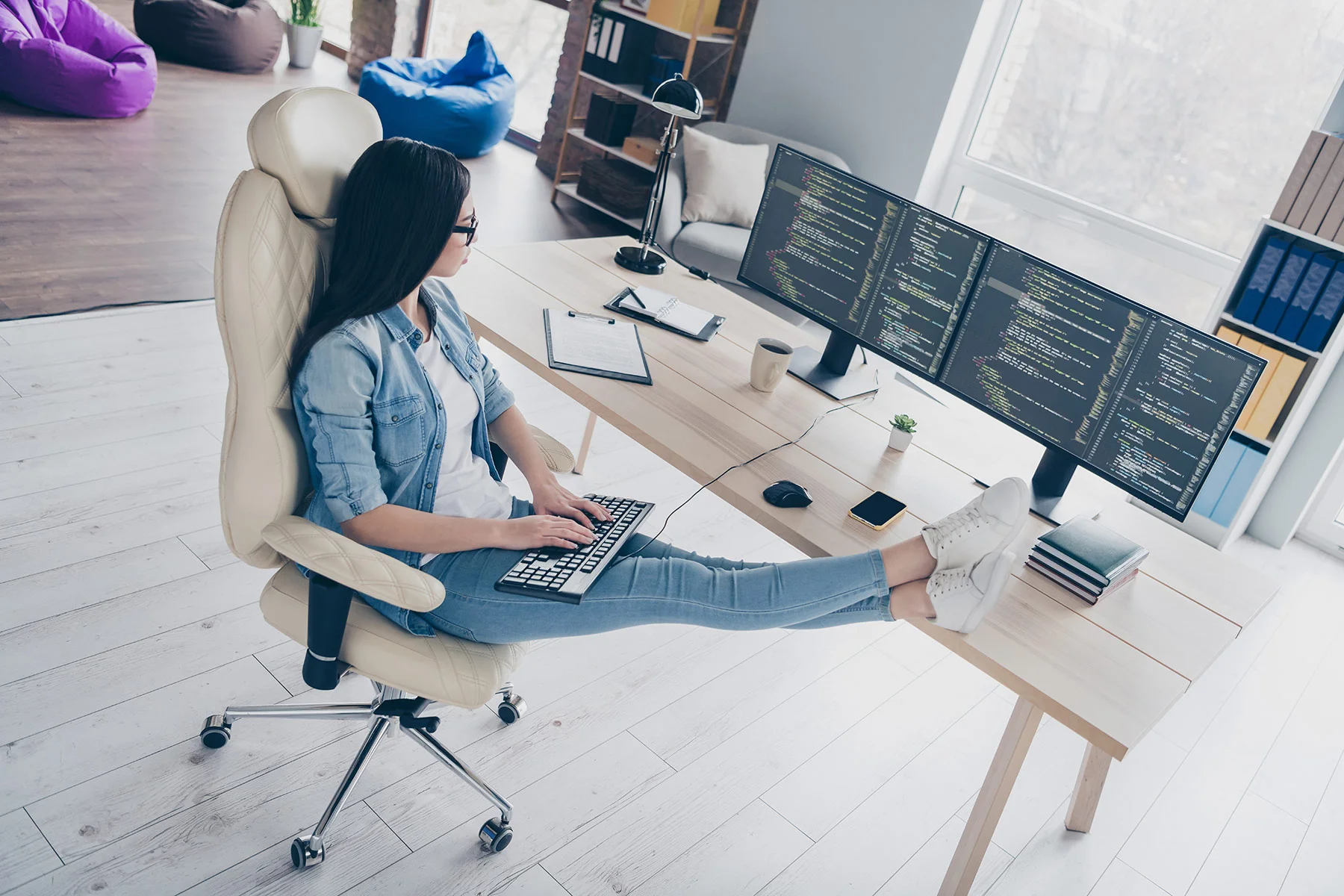 A woman works comfortably at a desk in a modern, hybrid office space that KARDENT architects can expertly design.